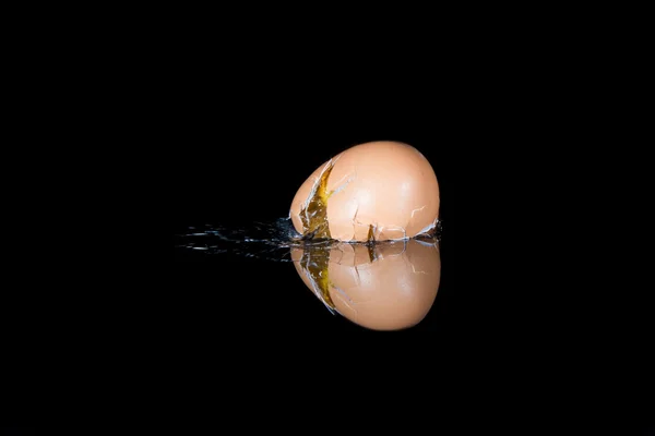 Ovo cair e quebrar na superfície brilhante preto com reflexão — Fotografia de Stock