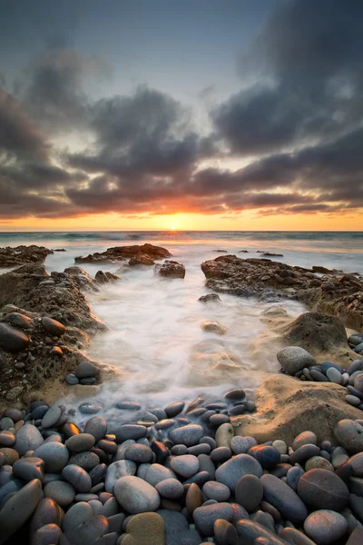Early morning landscape of ocean over rocky shore and glowing su — Stock Photo, Image