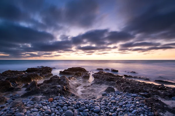Hajnali táj-óceán felett a sziklás parton, és izzó su Stock Kép