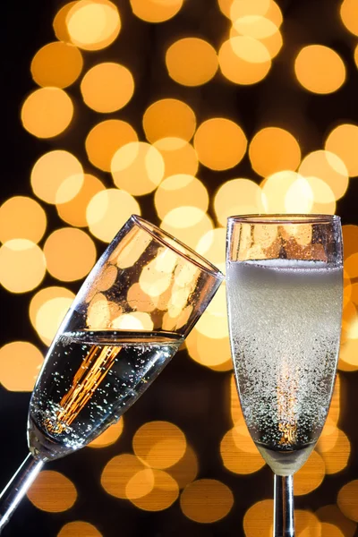 Two champagne glasses with bubbles and bokeh lights in the back