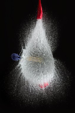 Balloon filled with water is popped with dart to make a mess clipart