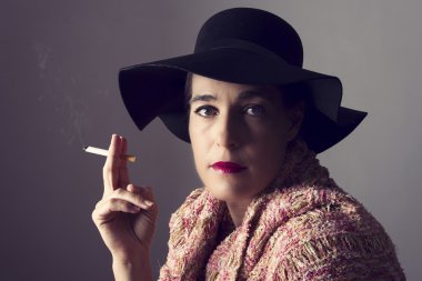 Siyah şapkalı Olgun kadın oturup Sigara
