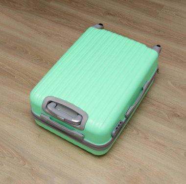 Açık yeşil plastik bavul yerde.