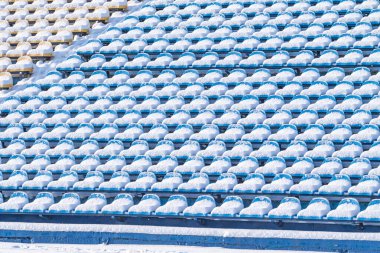 Kışın karlı havada stadyum koltukları. Kışın stadyumda karla kaplı çok renkli koltuklar. Kar yağışı sporu engeller. Temizlenmemiş stadyum.