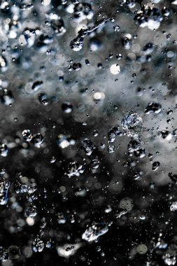 Karanlık arka planda su damlaları sınırlıdır. Kara zeminde donarak havaya düşen su damlaları..