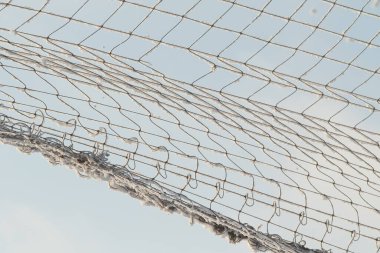 Mavi gökyüzüne karşı karda bir kafesin içinde örgü..