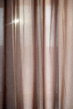 Penceredeki kumaş perdeler güneş dokusundan korunuyor.