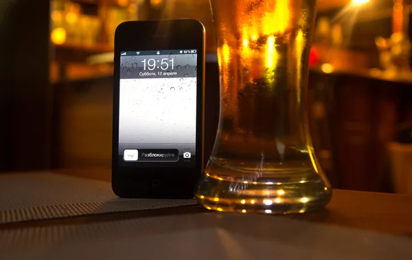Schermo del telefono e un bicchiere di birra — Foto Stock