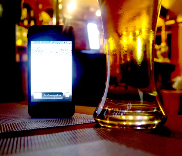 Schermo del telefono e un bicchiere di birra — Foto Stock