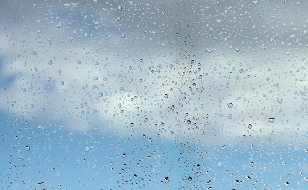 Wassertropfen auf Glas gegen blauen Himmel — Stockfoto