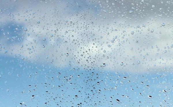 Vízcseppek az üvegen a kék ég ellen — Stock Fotó