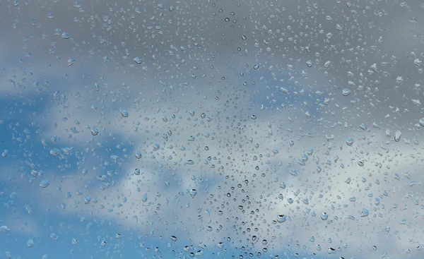 Wassertropfen auf Glas gegen blauen Himmel — Stockfoto