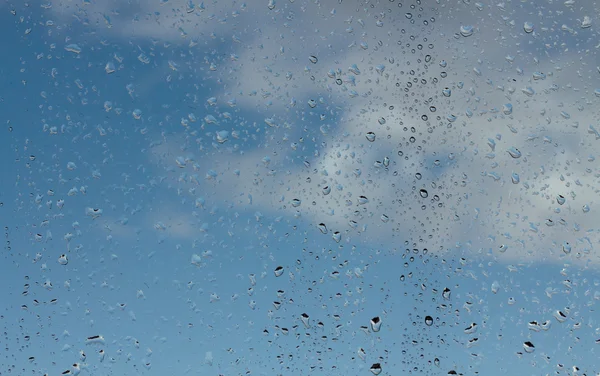 Gouttes d'eau sur verre contre ciel bleu — Photo