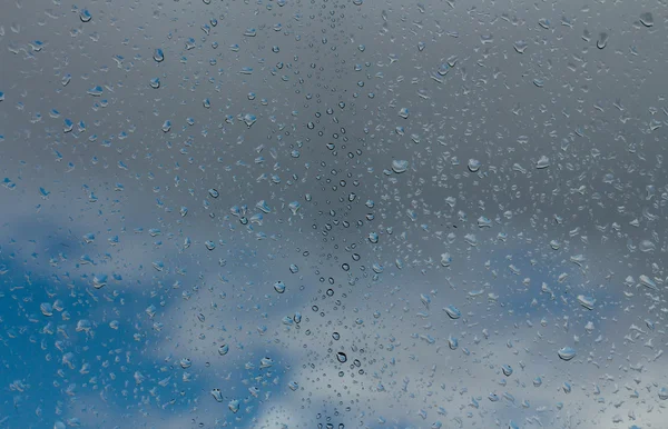 Gotas de agua sobre vidrio contra el cielo azul — Foto de Stock