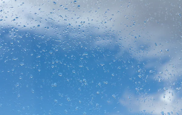 Σταγόνες νερού σε γυαλί κατά του γαλάζιου ουρανού — Φωτογραφία Αρχείου