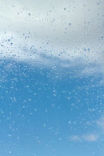 Gotas de agua sobre vidrio contra el cielo azul — Foto de Stock