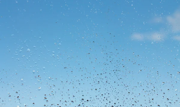 Gocce d'acqua su vetro contro cielo blu — Foto Stock