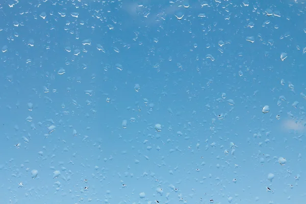 Vízcseppek az üvegen a kék ég ellen — Stock Fotó