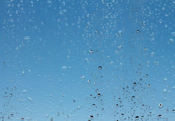 Gotas de água em vidro contra o céu azul — Fotografia de Stock