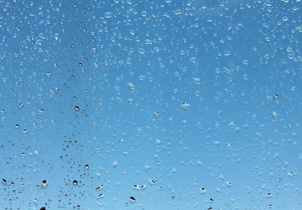 Gouttes d'eau sur verre contre ciel bleu — Photo