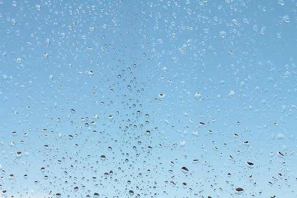 Voda kapky na sklo proti modré obloze — Stock fotografie