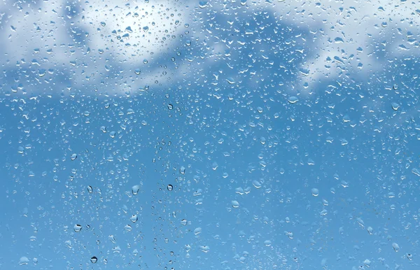 Gotas de água em vidro contra o céu azul — Fotografia de Stock