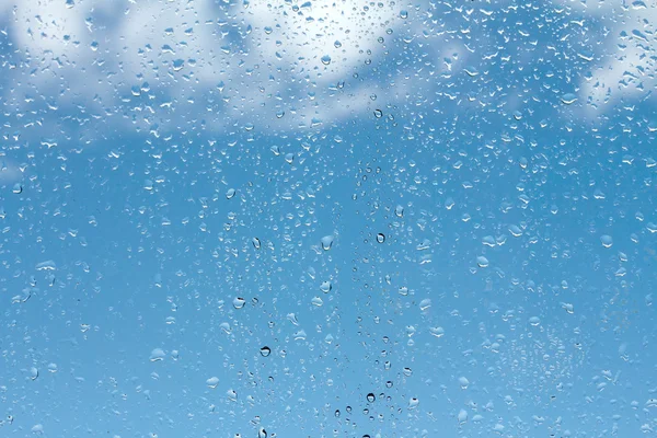 Gocce d'acqua su vetro contro cielo blu — Foto Stock
