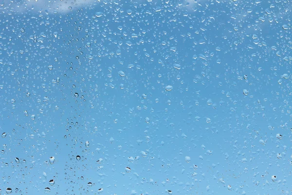 Wassertropfen auf Glas gegen blauen Himmel — Stockfoto