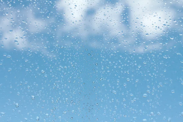 Gotas de agua sobre vidrio contra el cielo azul — Foto de Stock