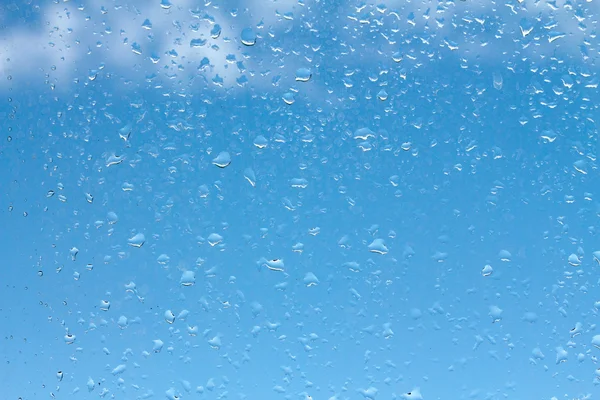 Wassertropfen auf Glas gegen blauen Himmel — Stockfoto