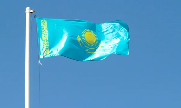 Cazaquistão agitando bandeira contra o céu azul — Fotografia de Stock