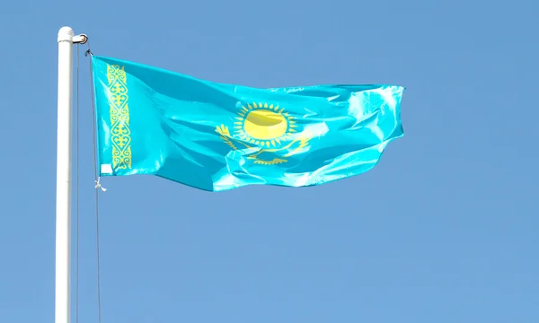 Cazaquistão agitando bandeira contra o céu azul — Fotografia de Stock
