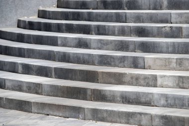 Aşınmış ve yıpranmış bir takım gri adımlar. Basamaklar betondan yapılmış ve merdiven deseninde düzenlenmiş. Adımlar, arka planla uyum sağladıkları için pek fark edilmiyor.