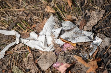 A pile of trash on the ground, including a white cloth and some leaves. Scene is one of neglect and disregard for the environment