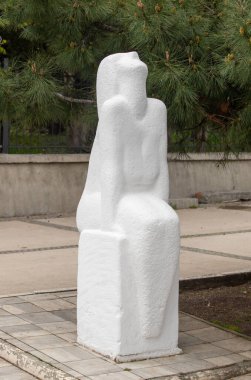 Bankta oturan beyaz bir kadın heykeli. Heykel betondan yapılmıştır ve tuğla bir geçide yerleştirilmiştir. Kadının duruşu ve bankın duruşu huzurlu bir izlenim veriyor.
