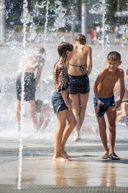 Petropavlovsk, Kazakistan - 18 Temmuz 2024: Çocuklar yaz sıcağında çeşmede serinleyebilir. Çocukları serinletmek için eğlenceli ve ferahlatıcı bir yol. Yaz tatili.
