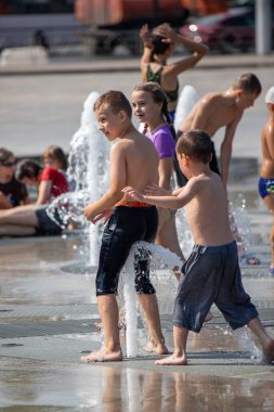 Petropavlovsk, Kazakistan - 18 Temmuz 2024: Çocuklar yaz sıcağında çeşmede serinleyebilir. Çocukları serinletmek için eğlenceli ve ferahlatıcı bir yol. Yaz tatili.