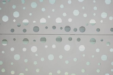 The wall is covered in a pattern of white circles, with each circle spaced out evenly. The circles are large and white, creating a sense of depth and texture on the wall. The overall effect is a clean