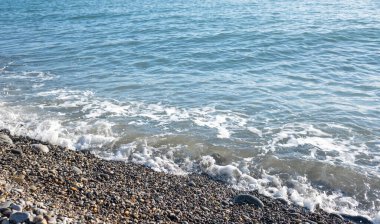 Seashore, small stones, sea wave. Marine background.