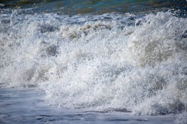 A sea wave breaks against the rocks, water splashes in the sky. Tidal wave.