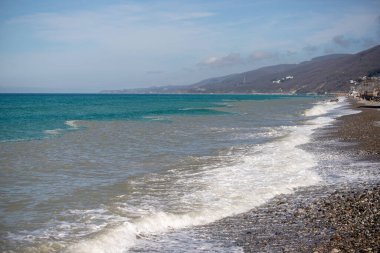 Seashore, small stones, sea wave. Marine background.