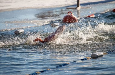 Suda bir yüzücü var ve suda birkaç şamandıra var. Şamandıralar turuncu ve beyaz.