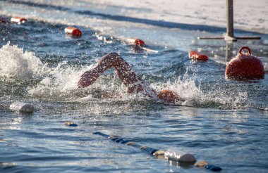 Suda bir yüzücü var ve suda birkaç şamandıra var. Şamandıralar kırmızı ve beyaz.