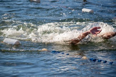 Bir adam elinde beyaz bir şamandırayla okyanusta yüzüyor. Su dalgalı ve adam ayakta kalmak için mücadele ediyor.