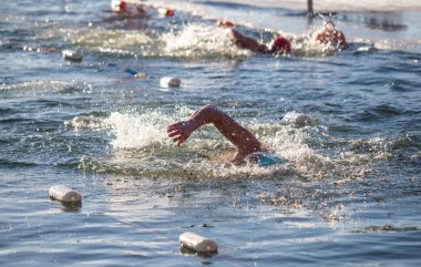 Bir adam elinde bir şişeyle suda yüzüyor. Su dalgalı ve adam ayakta kalmak için mücadele ediyor.