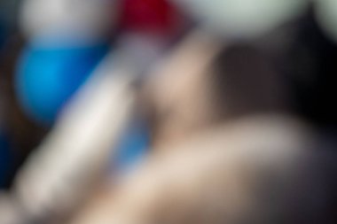 Mavi ve beyaz gömlekli bir kişinin bulanık görüntüsü. Kişi uzanıyor ve dinleniyor.