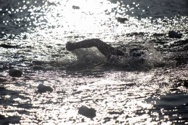 A swimmer is in the water, and the water is murky. The water is also very cold