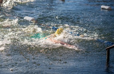 Bir yüzücü suyun içindedir, etrafa su sıçratır ve suyun serinliğinin tadını çıkarır.