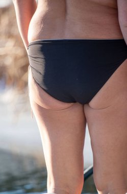 Bir kadın siyah bir bikini giyiyor ve suyun kenarında duruyor. Rahatlama ve rahatlama kavramı. Kadın sahilde vakit geçirmekten zevk alıyor.