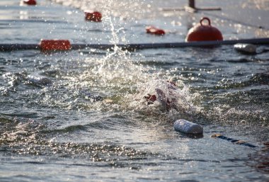 Suda bir yüzücü var ve bir şişe ve şamandıra da dahil olmak üzere yüzen birkaç nesne var.